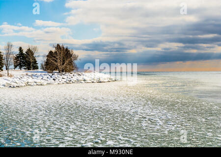 Paesaggio invernale scena mostrando il bianco della neve lungo l'acqua ghiacciata lago linea costiera su una bella giornata di sole con contrasto elevato sky Foto Stock