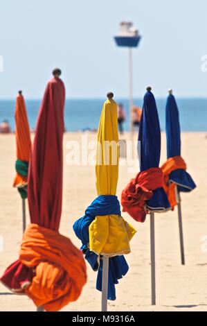 Ombrelloni sulla spiaggia sabbiosa a Deauville, giugno 2017, ombrelli arrotolata sulla mattina di sole.