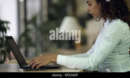 Donna al lavoro su laptop, telefono e carte sulla scrivania, atmosfera all ufficio della società Foto Stock