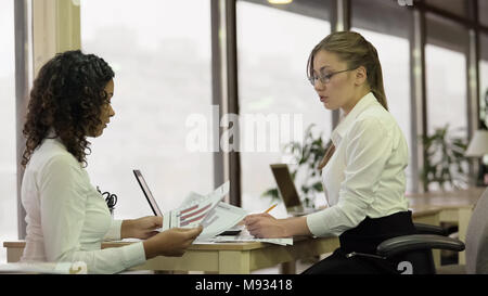 Femmina rigorosa team leader carte di controllo con il dipendente, progetto di brainstorming Foto Stock