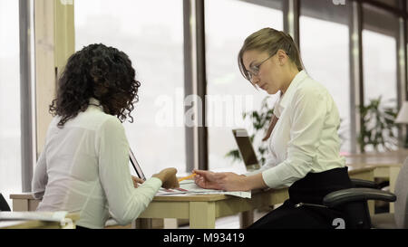 Bella femmina dipendenti carte di controllo, office team di lavoro sul progetto insieme Foto Stock