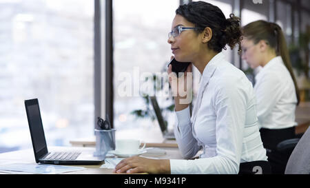 Femmina di lavoratore di ufficio colloqui sullo smartphone con client, accetta ordini del cliente Foto Stock