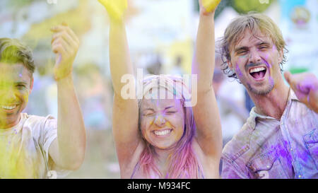 Emozionato i giovani gettare polvere colorata in aria, splendente di felicità Foto Stock