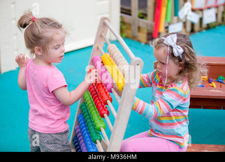 Due ragazze a giocare con un abaco presso una scuola materna nel Warwickshire, Regno Unito Foto Stock