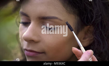 Trucco artisti preparazione bella giovane donna per sparare, migliorando le sopracciglia Foto Stock