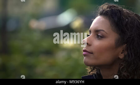 Trasognata biracial dai capelli ricci donna che guarda lontano, pensando a vita, primo piano Foto Stock