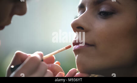 Le mani di truccatore applicando lip gloss, preparazione di bella sposa per matrimonio Foto Stock