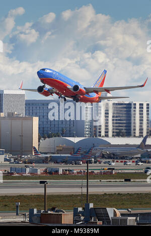 Southwest Airlines Boeing 737 aereo di linea che decollano dall'Aeroporto Internazionale di Los Angeles LAX, nuvole e coperta di neve Montagne di San Gabriel dietro. Foto Stock