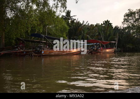 Quattro thailandese tradizionale barca adorna il accanto a una giungla sulla mae klond fiume non lontano dal mercato galleggiante di Amphawa, sul tramonto riflesso Foto Stock