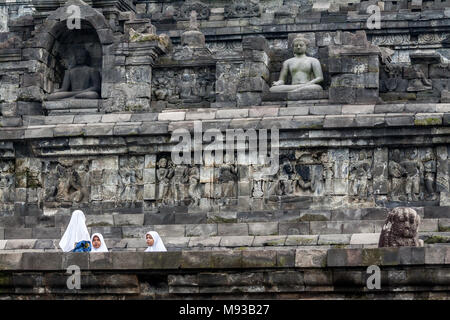 Il Borobudur tempio buddista e tre giovani ragazze musulmane di indossare islamica tradizionale cappelleria noto come hijab sopraffatte dal sito Patrimonio Mondiale dell'Unesco Foto Stock