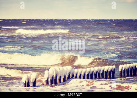 Congelati frangiflutti in legno in una giornata ventosa, dai toni di colore immagine, Mar Baltico in Polonia. Foto Stock