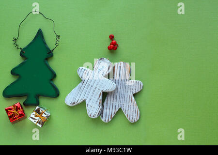 Vischio sopra due gingerbread persone baciare e un verde albero di Natale con due piccoli regali sotto albero di Natale su uno sfondo verde Foto Stock