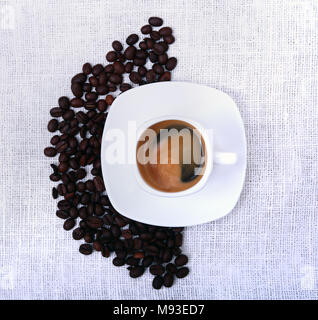 Classico espresso in tazza bianca e i chicchi di caffè su sfondo bianco. Vista dall'alto. Foto Stock