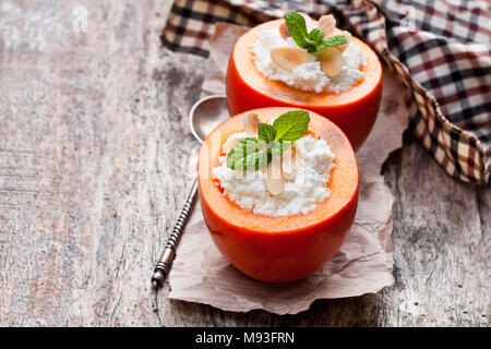 Persimmons dolce farcito con ricotta e mandorle sul tavolo di legno Foto Stock