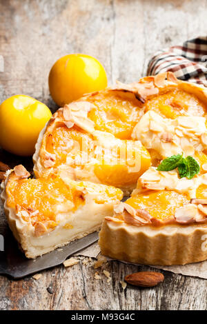 Deliziosa torta con prugna gialla e mandorle sul tavolo di legno Foto Stock