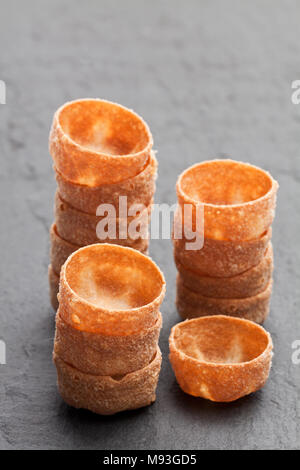 Pile di croustades pasticceria croccante casi sulla pietra nera sullo sfondo Foto Stock