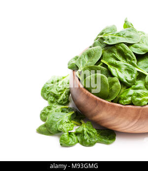 Le foglie di spinaci in ciotola di legno isolato su sfondo bianco Foto Stock