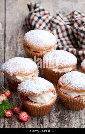 Tortine farcite con crema bianca e fragole selvatiche sul tavolo di legno Foto Stock