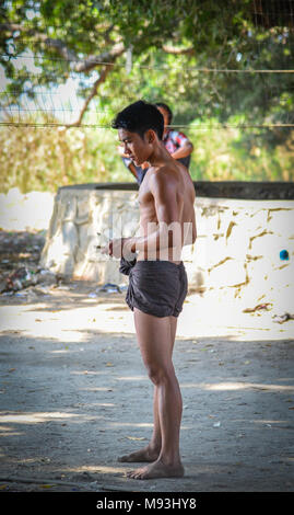 Mandalay, Myanmar - Feb 11, 2017. Un uomo birmano con longyi permanente al villaggio di Mandalay, Myanmar. Foto Stock