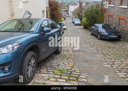 Auto parcheggiate su Kings Arms Hill, una storica strada di ciottoli su una ripida collina nella storica città mercato su Arundel, West Sussex, in Inghilterra, Regno Unito. Foto Stock