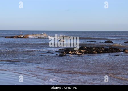 Onde che si infrangono su alcuni parzialmente sommerso le rocce in Roker, Sunderland, Wearside Foto Stock