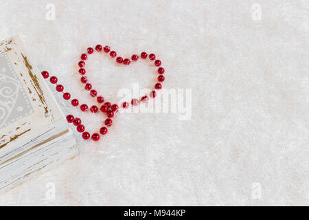 Cuore rosso realizzato da tallone collana su sfondo bianco Foto Stock