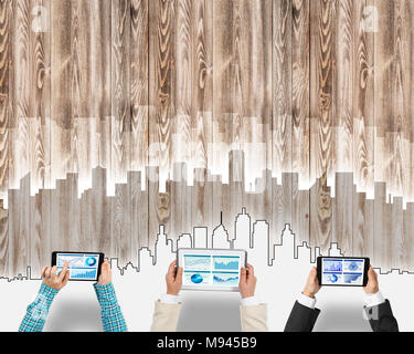 Un gruppo di tre persone con i dispositivi in mani lavorando insieme come simbolo del collegamento in rete e comunicazione Foto Stock