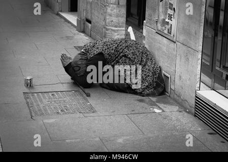 Una vecchia signora pregando e mendicando per denaro su strada Foto Stock