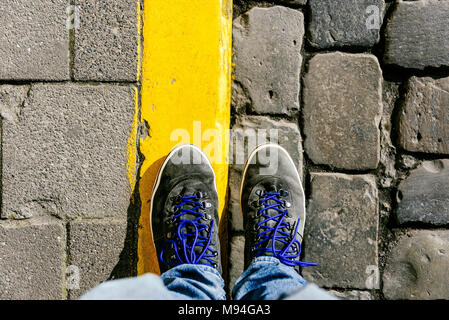 Fino a raggiungere un incrocio a dover decidere circa il passato, ora e in futuro simboleggiato da due piedi e scarpe in piedi su due differenti materiali percorso da abo Foto Stock