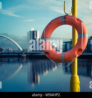 Orange salvagente con il fiume Clyde e ponte ad arco in background Foto Stock