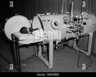 Un operatore medico dimostra un nuovo paziente con ossigeno iperbarico la camera di American College of Surgeons congresso a Chicago, ca. 1964. Foto Stock
