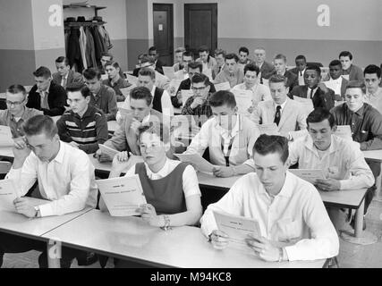 Noi studenti di scuola superiore di guardare al di sopra di un test standardizzato esame che sono in procinto di prendere, ca. 1958. Foto Stock