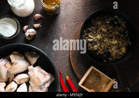 Fritto di pollo a pezzi in una padella, cipolle e peperoncino. Il cibo indiano in orizzontale Foto Stock