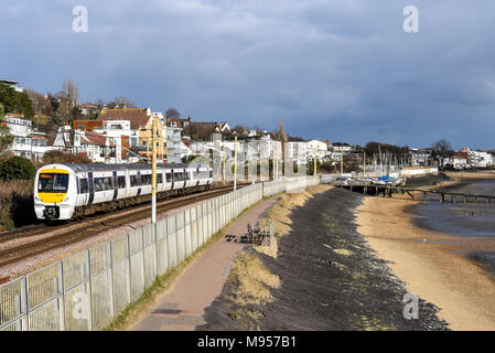 C2C treno ferroviario passando dall estuario del Tamigi a Chalkwell Beach, Southend on Sea, Essex. Classe 357 Electric Multiple Unit dal mare e dalla spiaggia. Yachts Foto Stock