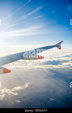 Vista da una finestra di aereo in volo per l'ala di aeroplano con cielo blu e nuvole stratocumulus visibile Foto Stock