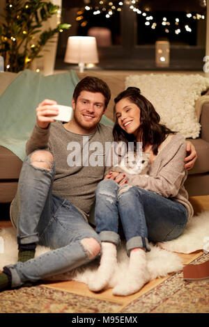 Coppia felice tenendo selfie tramite smartphone a casa Foto Stock