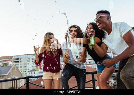 Diversi gruppi di amici celebrare la festa con champagne. Gli uomini e le donne aventi un grande tempo al partito sul tetto. Foto Stock