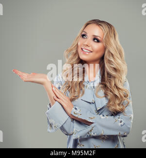 Donna sorridente che mostra vuoto lo spazio di copia sulla mano aperta e guardando in alto Foto Stock