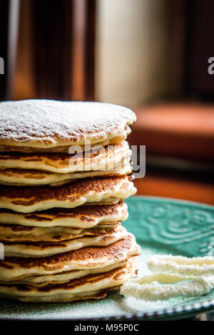 American pancake con zucchero su un verde pastello piastra rustico Foto Stock