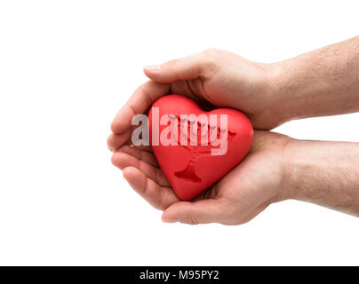 Cuore rosso con impresso il menorah in mani dell'uomo. Foto Stock