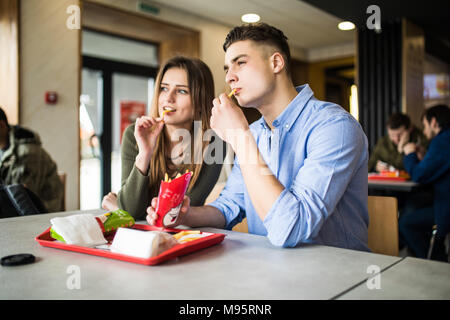 Bello sorridente giovane godendo di patatine fritte, divertirsi insieme. Il consumismo, il cibo, il concetto di stile di vita Foto Stock