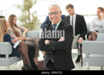 Sorridente imprenditore senior sullo sfondo del team aziendale Foto Stock