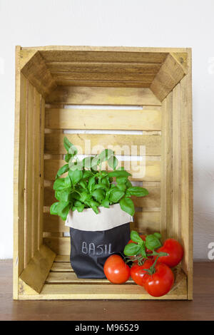 Fresche e mature garden pomodori e basilico su sfondo di legno di una gabbia in legno con spazio di copia Foto Stock