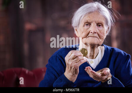 Senior donna con paio di bitcoins, dimostrando uno di loro, mani di messa a fuoco Foto Stock
