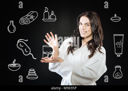 Donna felice in un accappatoio mostrando il suo presente e sorridente Foto Stock