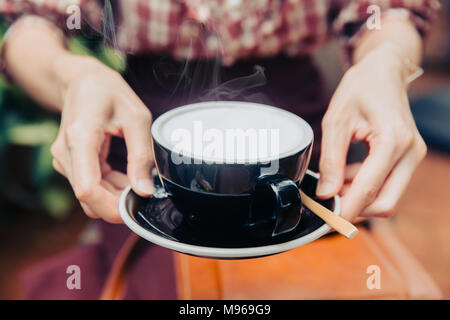 Closeup tenere in mano servire caldo latte cremoso bianco bibita salutare per tutti i giorni Foto Stock