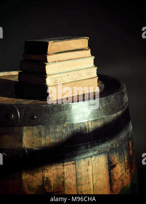 Pila di libri vecchi su un barile di whiskey con ombre Foto Stock