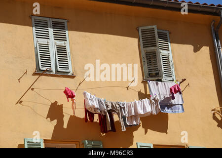 Biancheria in asciugatura vestiti appesi al di fuori della finestra di un antico edificio nel centro storico di Menton, Francia / Costa Azzurra Foto Stock