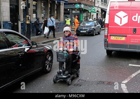 Uomo su una mobilità scooter a Londra vicino alle automobili. Foto Stock