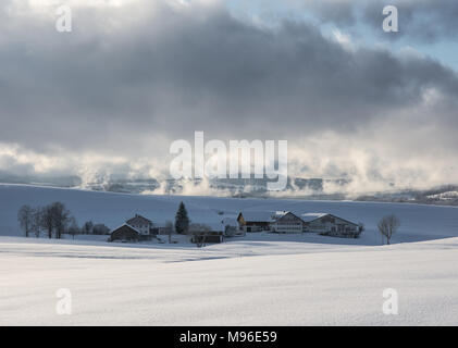 Basso appeso nuvole sopra agriturismi in Algovia invernale Foto Stock